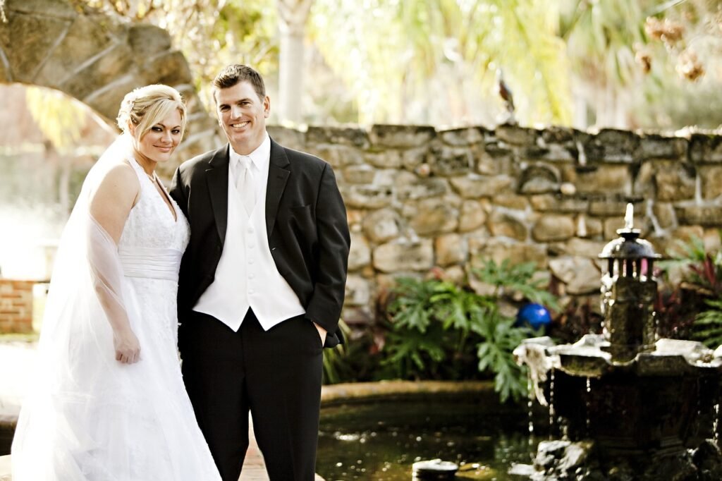 Smiling bride and groom by a stone fountain, symbolizing couples love and a lasting bond.